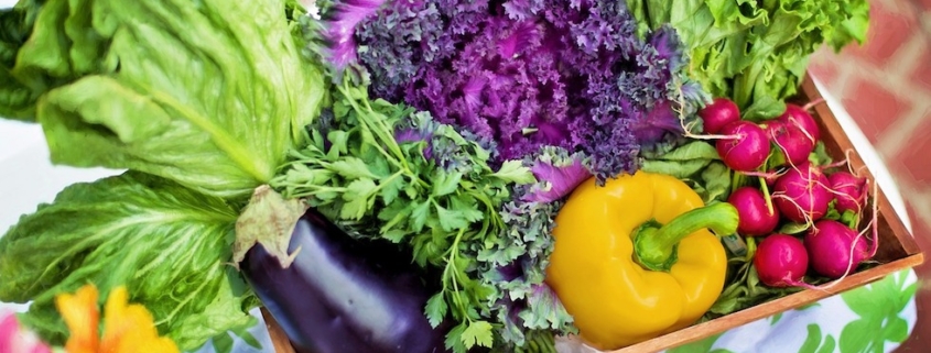 Fresh summer vegetables in a box on a bright tablecloth.